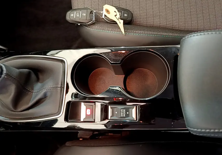 Vue plongeante sur la console centrale noire du Peugeot 208 blanc, avec levier de vitesse manuel et porte-gobelets doubles.