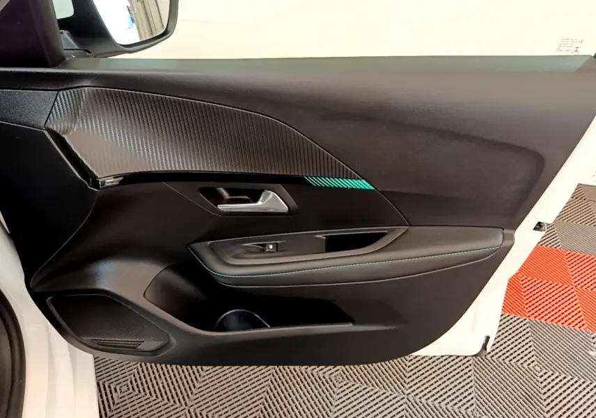 Gros plan sur la porte avant gauche blanche d'une Peugeot 208 2020 avec garniture noire et surpiqûres bleues.