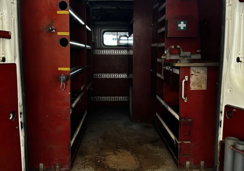 Vue arrière ouverte du Citroën Jumper blanc montrant l'intérieur aménagé avec étagères rouges et espace de rangement.