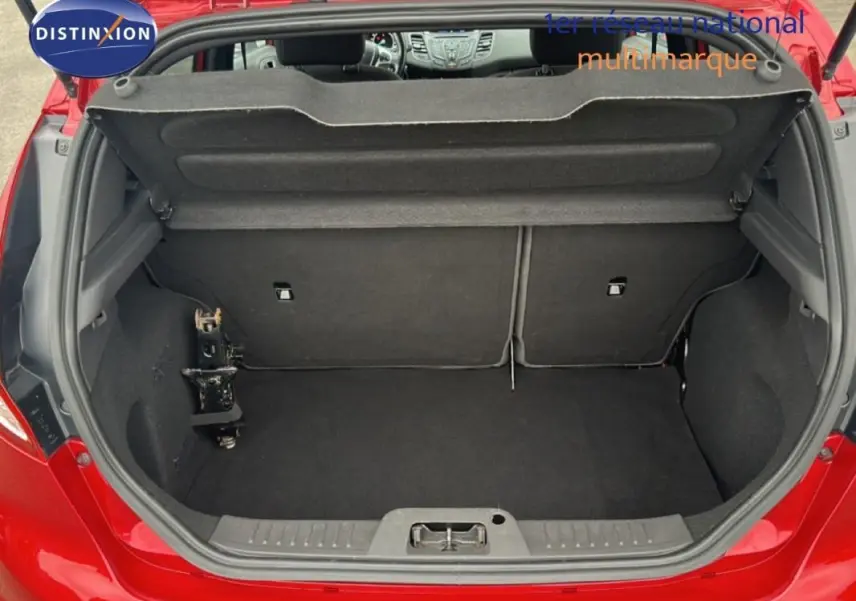 Coffre ouvert d'une Ford Fiesta rouge vue de l'arrière, montrant l'espace de chargement et l'intérieur noir.