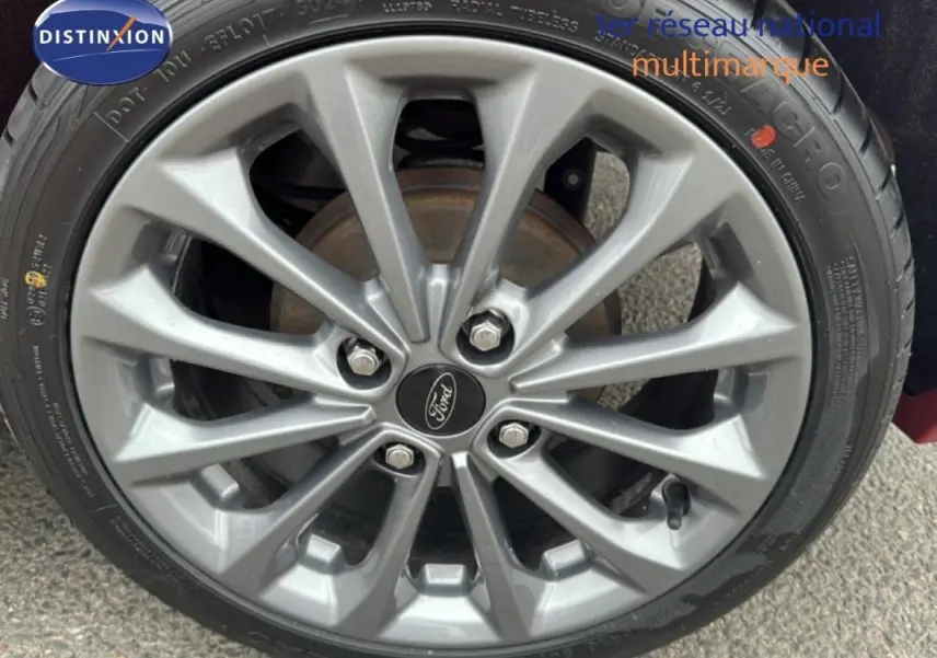 Gros plan sur la jante alliage 16 pouces grise de la Ford Fiesta rouge, avec logo Ford au centre.