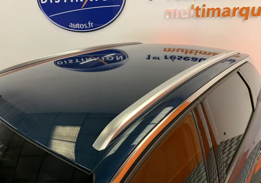 Toit panoramique et barres de toit argentées sur un Peugeot 3008 bleu Célèbes vu de dessus côté droit.