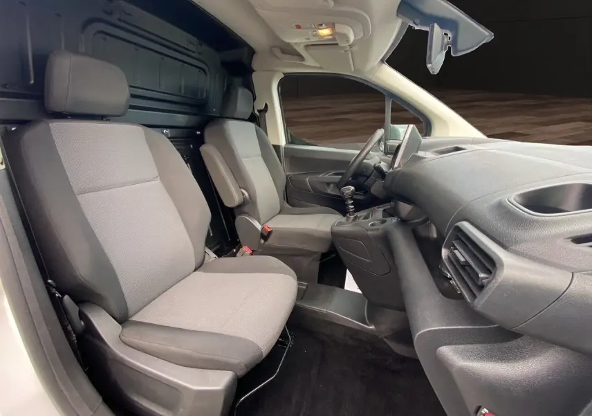 Vue intérieure côté conducteur du Citroën Berlingo 2019, sièges gris et tableau de bord noir avec levier de vitesses manuel.