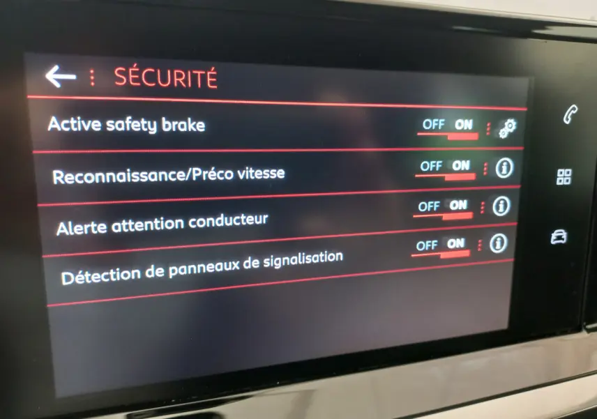 Écran tactile central affichant les options de sécurité du Peugeot 208 blanc, vue rapprochée de l'intérieur.