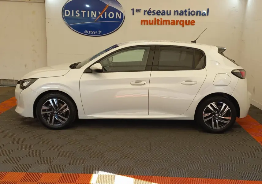 Profil côté gauche d'une Peugeot 208 PureTech 100 S&S Allure blanche, en intérieur sur sol gris et orange.