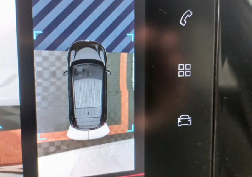 Affichage écran tactile montrant la vue aérienne d'une Peugeot 208 blanche en stationnement, avec capteurs de proximité visibles.