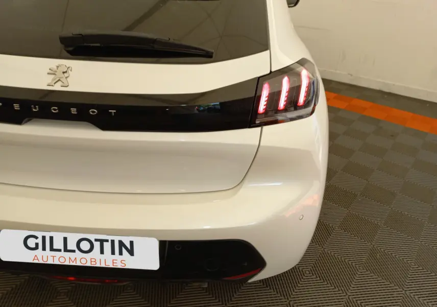 Vue arrière droite d'une Peugeot 208 blanche avec feux arrière LED et logo lion sur le hayon.
