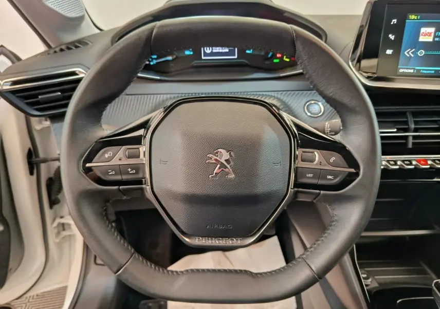 Vue rapprochée du volant cuir noir de la Peugeot 208 électrique Active Business R avec tableau de bord digital et écran tactile.
