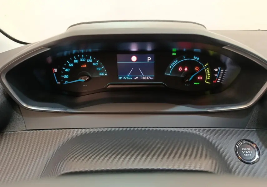 Tableau de bord de Peugeot 208 électrique blanc, vue frontale centrée sur l'affichage numérique et le bouton start/stop.