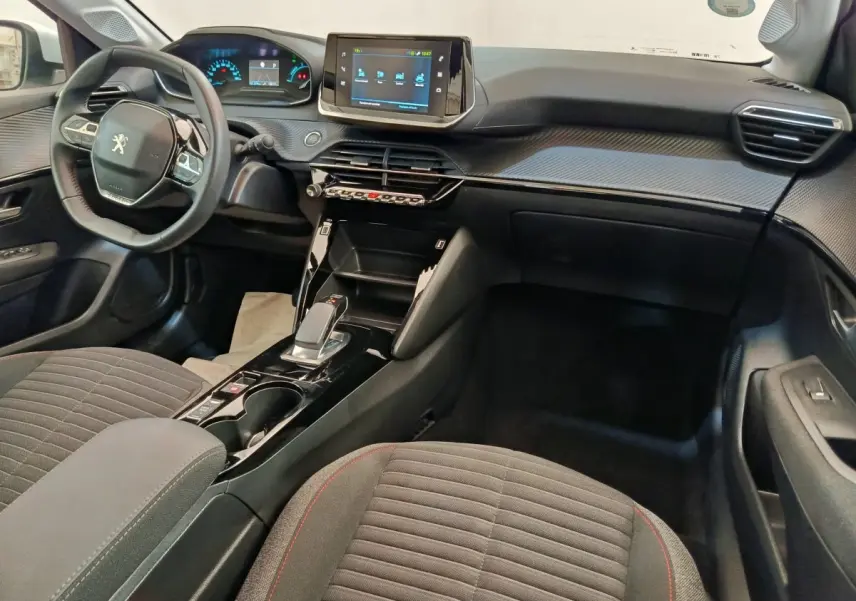 Intérieur de la Peugeot 208 électrique 2021 vu côté passager, tableau de bord noir avec écran tactile central.