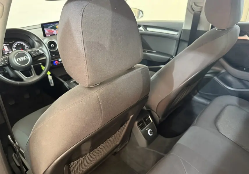 Vue intérieure arrière de l'Audi A3 Business Line 2018, sièges tissu gris et tableau de bord avec écran central.