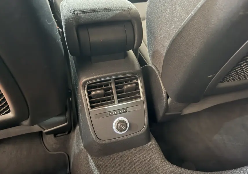 Vue rapprochée des aérateurs arrière et prise 12V entre les sièges avant noirs de l'Audi A3 Business Line 2018.
