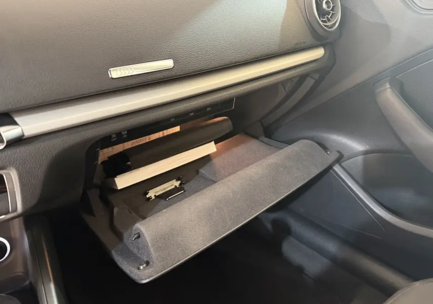 Gros plan sur la boîte à gants ouverte de l'Audi A3 2.0 TDI 150 Business Line, intérieur noir.