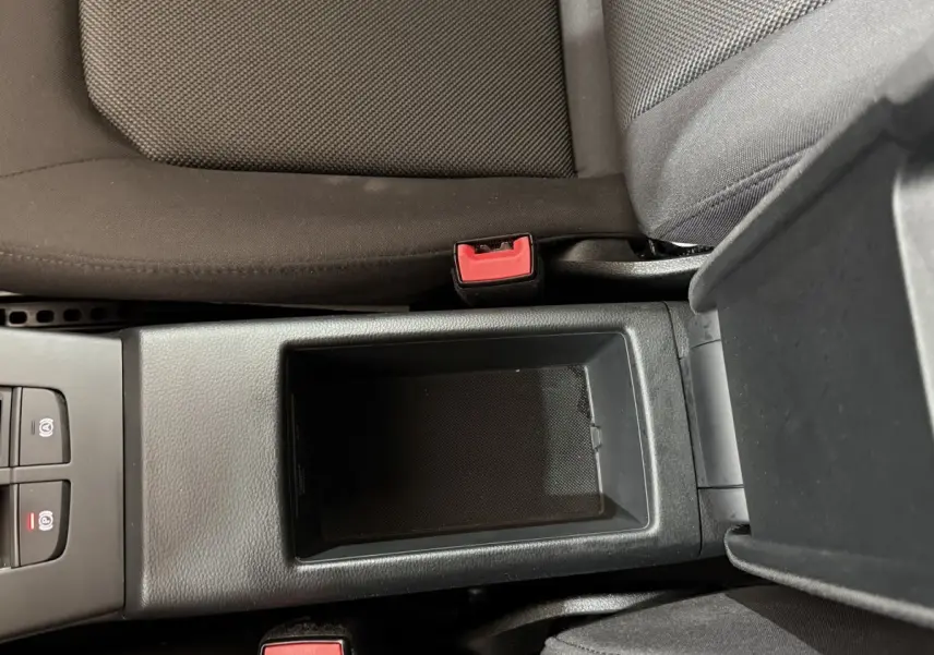 Vue plongeante sur la console centrale noire entre les sièges avant gris foncé d'une Audi A3 bleu 2018.