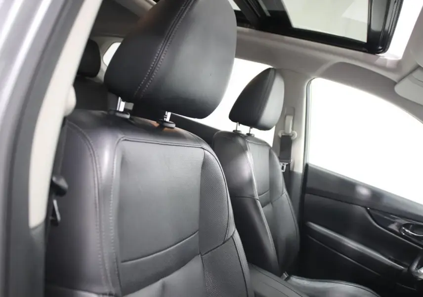 Vue intérieure avant du Nissan X-TRAIL 1.7 D 150 avec sièges cuir noirs et toit ouvrant panoramique ouvert.