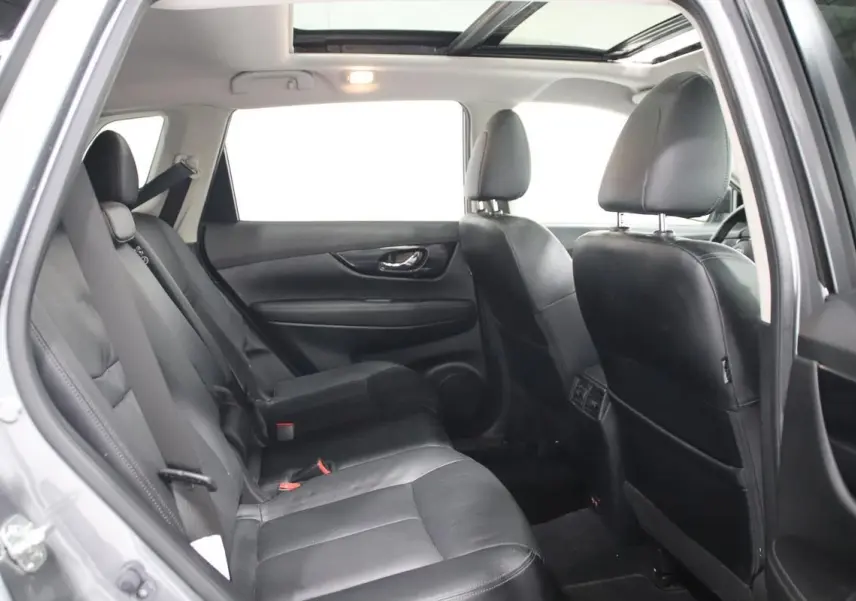 Vue intérieure côté gauche du Nissan X-TRAIL 2021 gris métallisé, montrant les sièges arrière en cuir et le toit ouvrant panoramique.