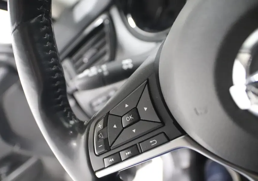 Gros plan sur les commandes au volant en cuir noir du Nissan X-Trail gris métallisé, côté gauche.