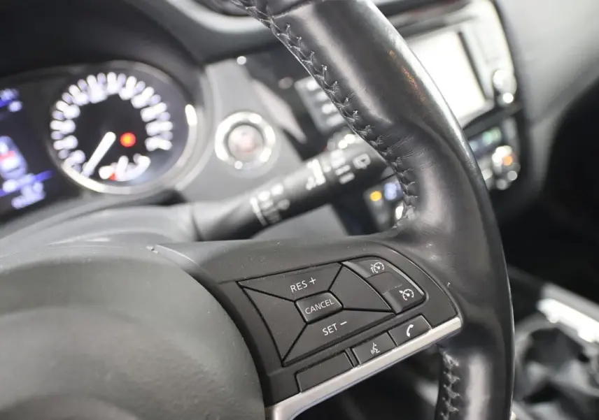 Gros plan sur le volant cuir noir du Nissan X-TRAIL 2021, montrant les commandes de régulateur de vitesse et téléphone.