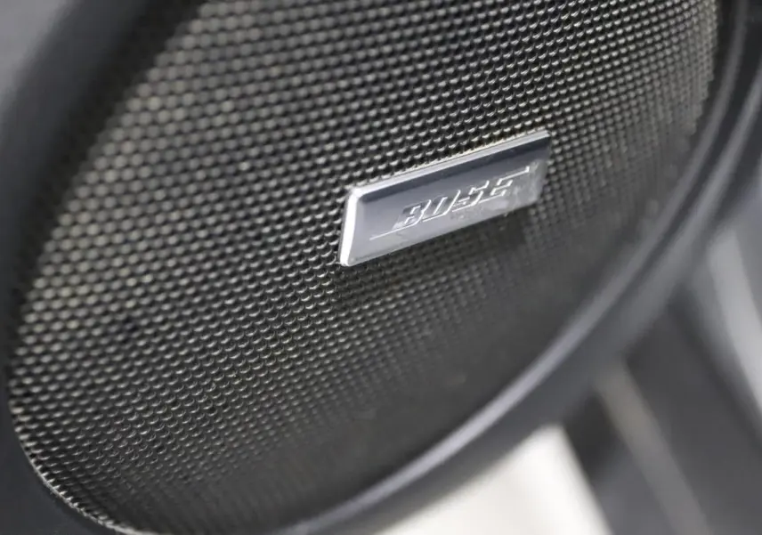 Gros plan sur l'enceinte Bose noire intégrée dans la porte intérieure du Nissan X-Trail gris métallisé.