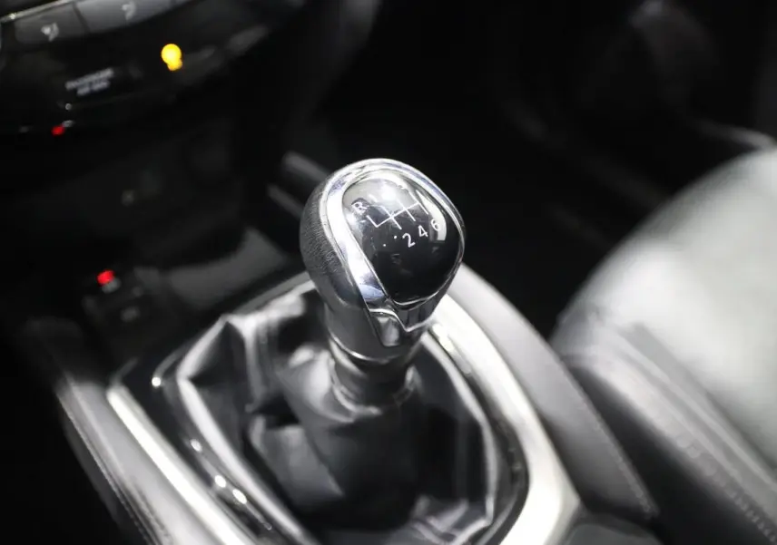 Gros plan sur le levier de vitesses manuel noir et chrome du Nissan X-Trail 1.7 D gris métallisé, intérieur cuir noir.