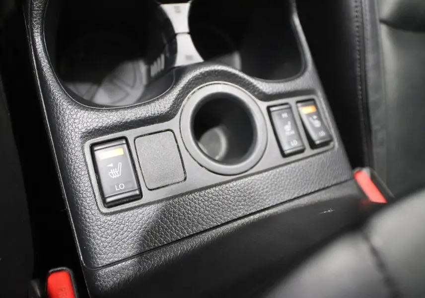 Gros plan sur les commandes des sièges chauffants en cuir noir du Nissan X-Trail 1.7 D 150, console centrale.