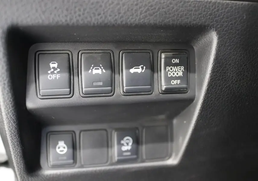 Gros plan sur les boutons de commande noirs du tableau de bord du Nissan X-TRAIL 1.7 D 150 gris métallisé.