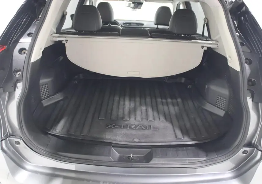 Coffre ouvert d'un Nissan X-Trail gris métallisé, vue arrière montrant le tapis de coffre avec logo X-TRAIL.
