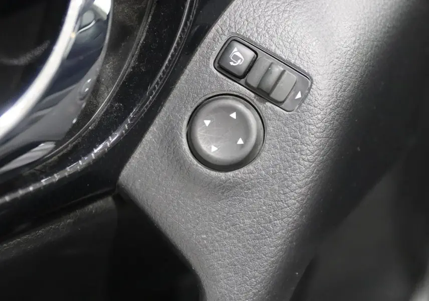 Gros plan sur les commandes de réglage des rétroviseurs intérieurs en plastique noir du Nissan X-Trail 1.7 D 150 gris métallisé.