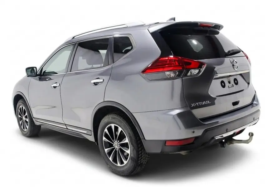 Vue 3/4 arrière droite d'un Nissan X-Trail gris métallisé avec attelage et toit ouvrant visible.