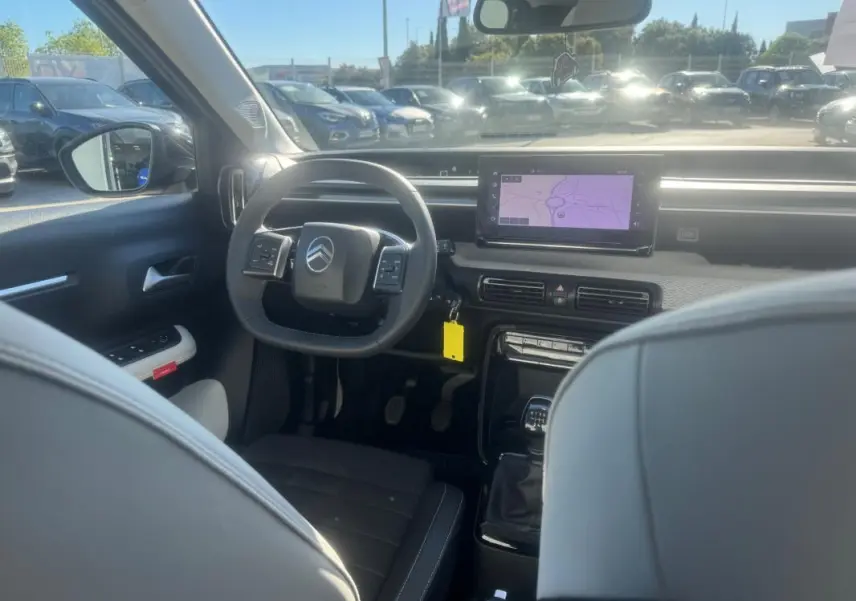 Vue intérieure avant de la Citroën C3 gris 2025, montrant le volant, écran tactile et levier de vitesse manuel.