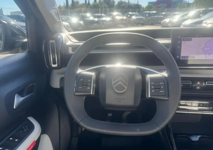 Vue intérieure centrée sur le volant de la Citroën C3 gris 2025, avec commandes intégrées et écran tactile visible.