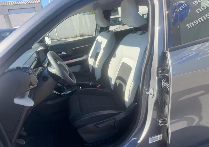 Vue intérieure côté conducteur de la Citroën C3 gris 2025, montrant les sièges bicolores et le volant avec commandes intégrées.