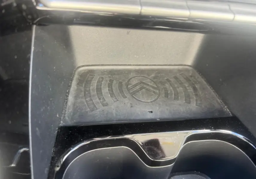 Gros plan sur le compartiment de recharge sans fil avec logo Citroën, intérieur noir de la C3 Turbo 2025.