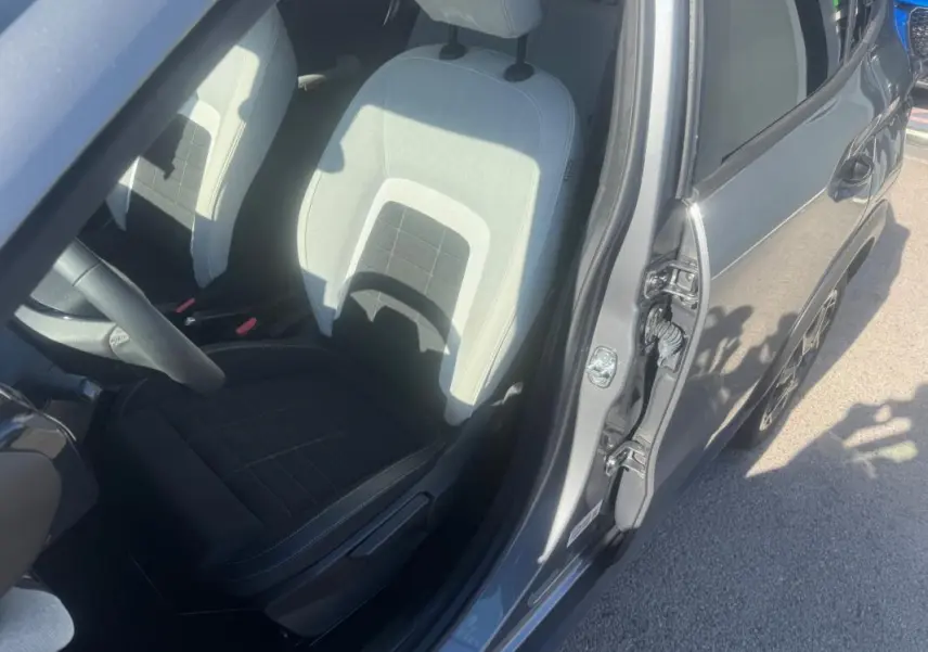 Vue intérieure côté conducteur d'une Citroën C3 gris 2025, montrant le siège avant clair et foncé avec portière ouverte.