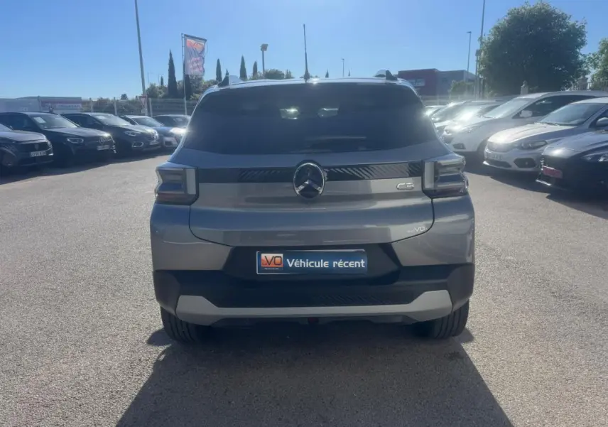 Vue arrière d'une Citroën C3 gris métallisé garée en extérieur sous un ciel ensoleillé.