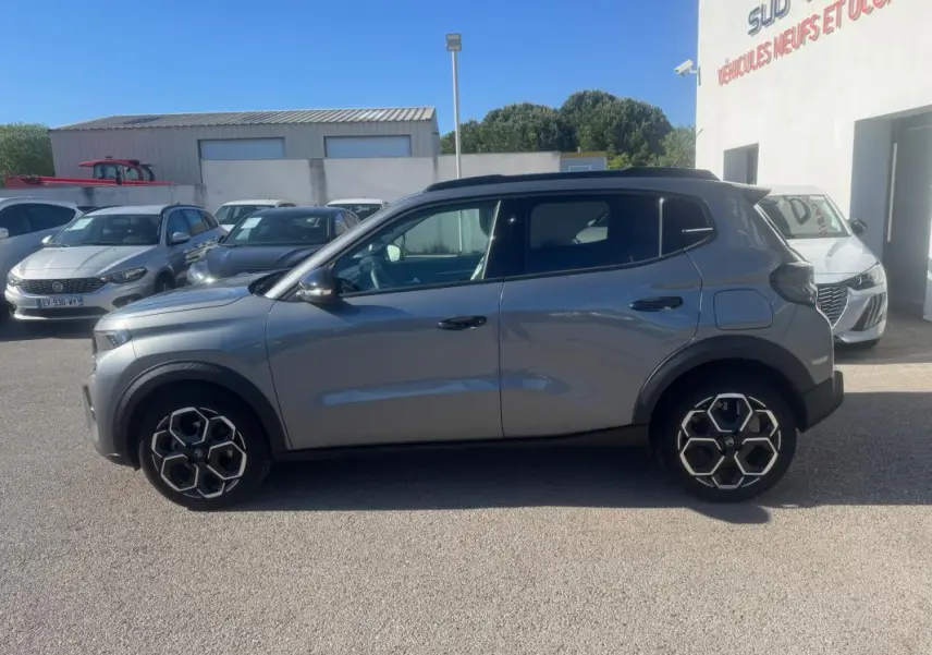 Vue de profil côté gauche d'une Citroën C3 gris 2025 avec jantes alliage 17 pouces et barres de toit noires.