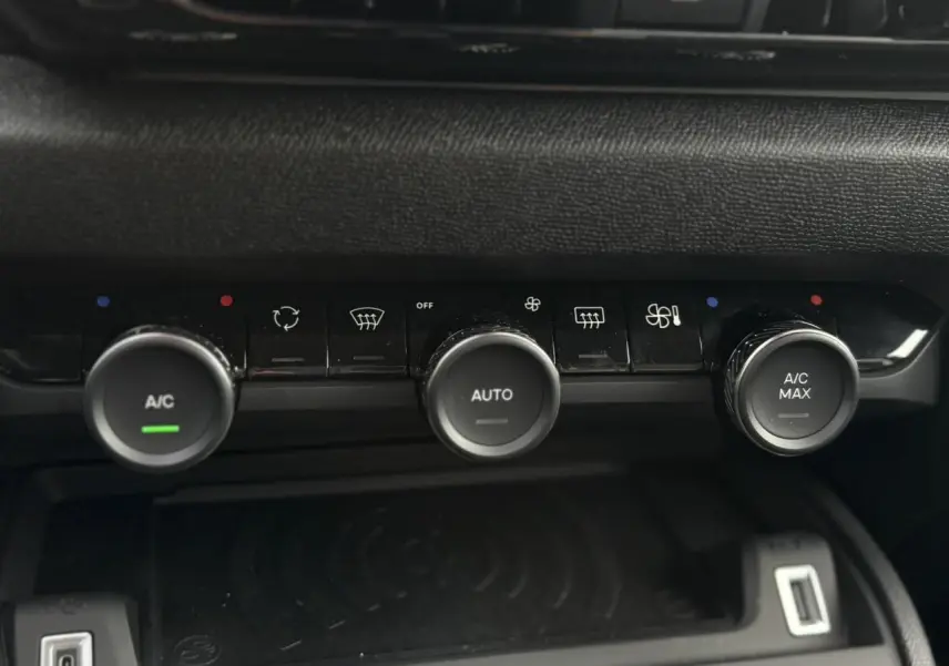 Gros plan sur la console centrale de la Citroën C4 Hybrid 2025, avec commandes de climatisation et recharge sans fil.