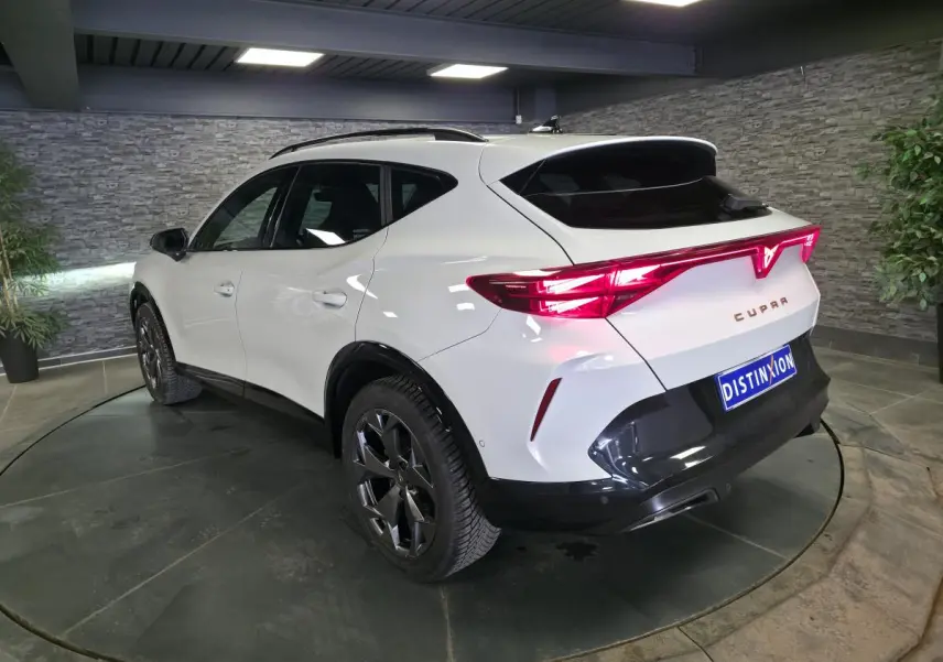 Vue 3/4 arrière droite du CUPRA Formentor blanc avec feux arrière en bandeau lumineux et jantes alliage noires.