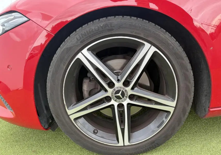 Gros plan sur la jante alliage 18 pouces à 5 doubles branches noir et naturel brillant d'une Mercedes Classe A rouge, côté avant gauche.