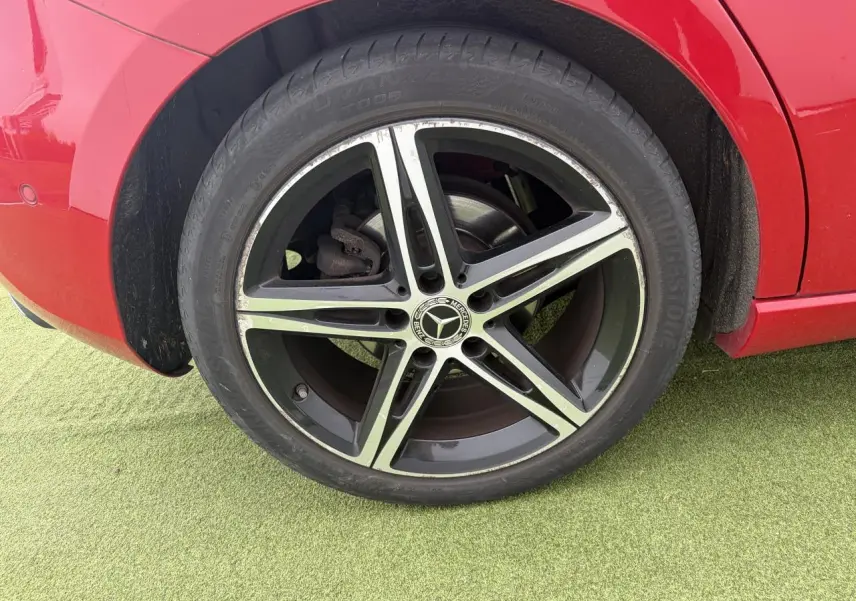 Gros plan sur la jante alliage 18 pouces noire et chromée d'une Mercedes Classe A rouge, vue côté arrière droit.