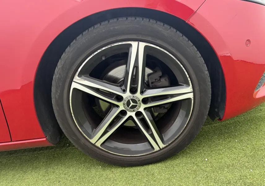 Gros plan sur la roue avant gauche rouge d'une Mercedes Classe A avec jante alliage 5 branches noire et argent.