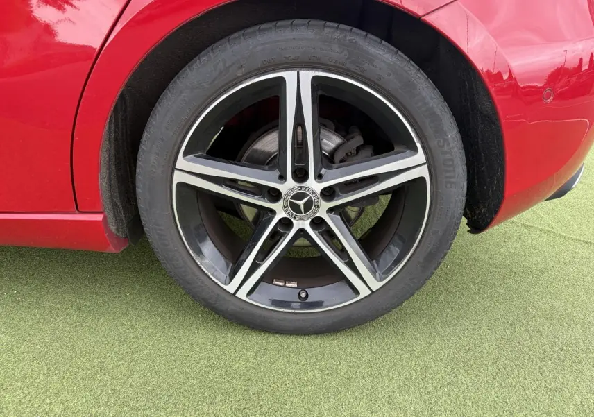 Gros plan sur la roue arrière droite d'une Mercedes Classe A rouge avec jante alliage 5 branches noir et argent.