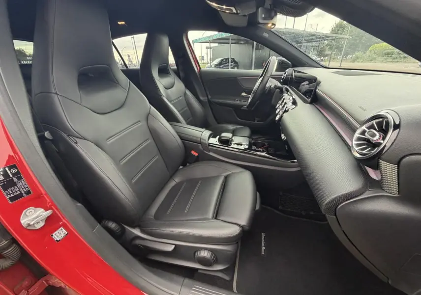 Intérieur avant droit d'une Mercedes Classe A rouge 2019 avec sièges cuir noir et tableau de bord moderne.
