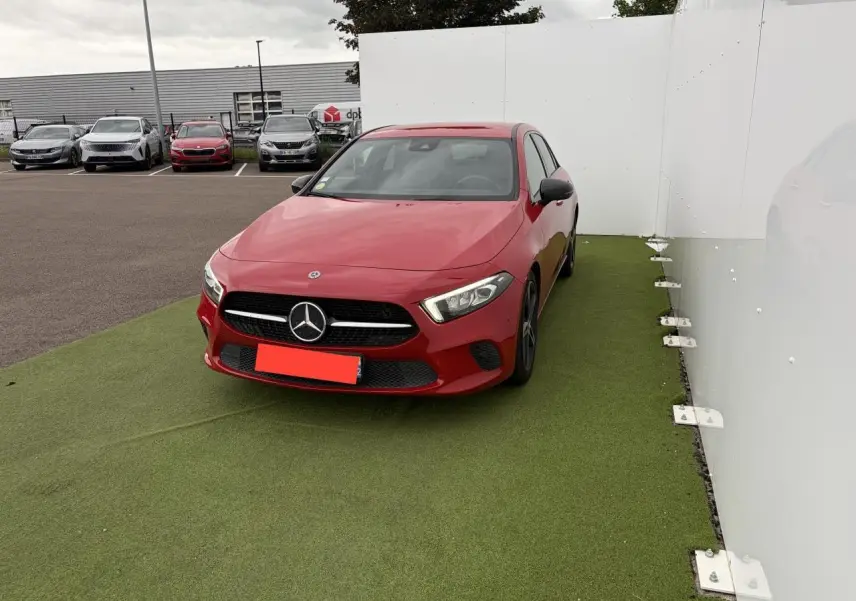 Mercedes Classe A rouge vue de face en léger angle droit, avec calandre noire et logo étoile bien visible.