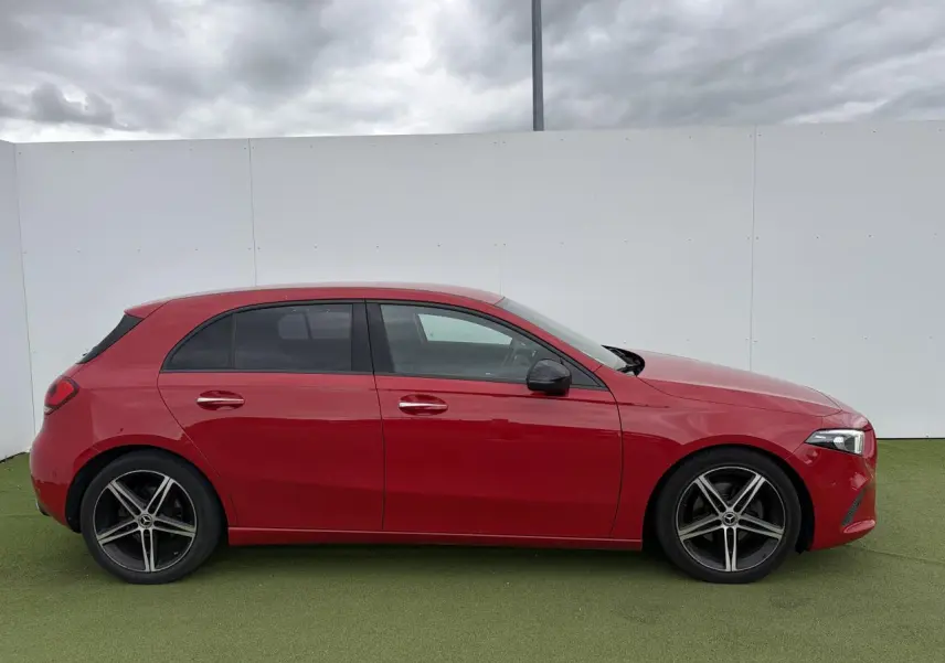 Vue de profil côté gauche d'une Mercedes Classe A rouge avec jantes alliage sport à 5 branches.