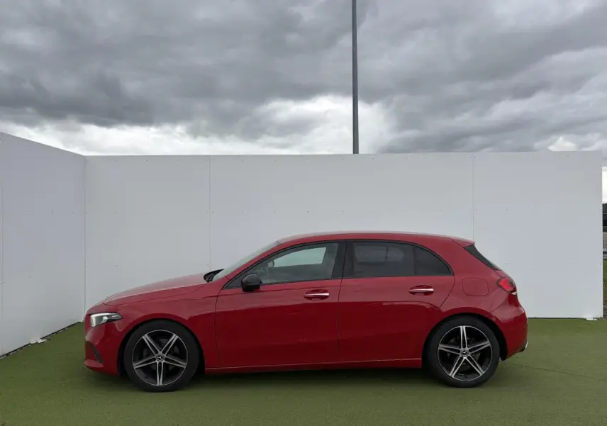 Vue latérale droite d'une Mercedes Classe A rouge avec jantes alliage noires à 5 branches, sur fond neutre extérieur.