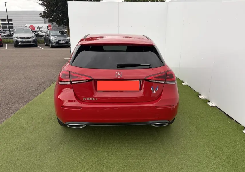 Vue arrière d'une Mercedes Classe A 180d rouge avec vitres teintées et doubles sorties d'échappement chromées.