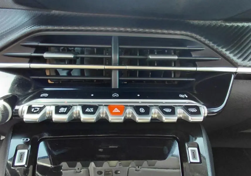 Gros plan sur la console centrale du Peugeot 208 gris 2025, avec boutons de commande et aérateurs noirs.