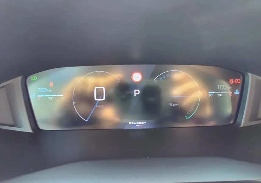 Tableau de bord numérique de Peugeot 208 Hybrid 110 ch en vue frontale, affichant vitesse et autonomie.