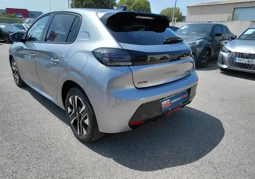 Vue 3/4 arrière gauche d'une Peugeot 208 gris clair avec jantes alliage et feux arrière noirs, stationnée en extérieur.